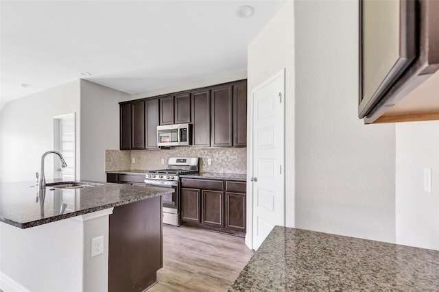 214 Kickapoo Dr, Anahuac, TX 77514 - kitchen with appliances with stainless steel finishes, tasteful backsplash, dark stone counters, dark brown cabinetry, and light wood-style floors