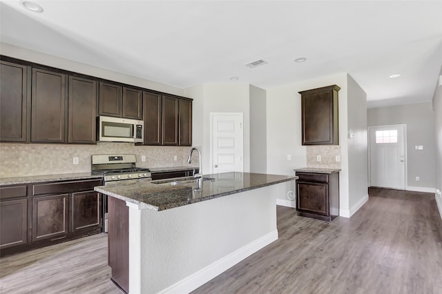 214 Kickapoo Dr, Anahuac, TX 77514 - kitchen featuring appliances with stainless steel finishes, dark stone countertops, tasteful backsplash, and light wood finished floors