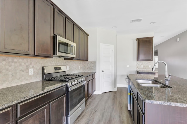 214 Kickapoo Dr, Anahuac, TX 77514 - kitchen with appliances with stainless steel finishes, dark stone countertops, wood finished floors, decorative backsplash, and dark brown cabinets