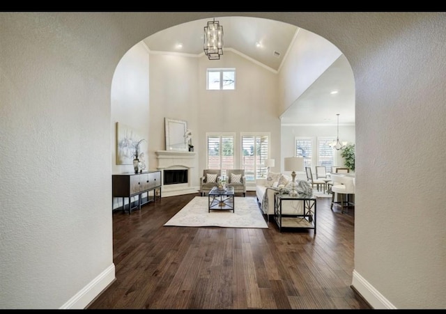 5011 Anthony Springs Ln, Sugar Land, TX 77479 - living room with a textured wall, a chandelier, dark wood-style flooring, arched walkways, and a fireplace with raised hearth