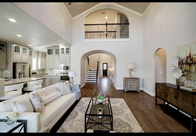 5011 Anthony Springs Ln, Sugar Land, TX 77479 - living area with arched walkways, dark wood-style flooring, stairway, ornamental molding, and high vaulted ceiling