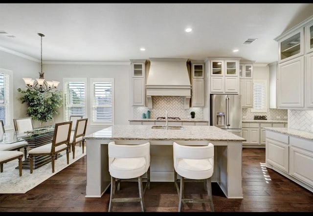 5011 Anthony Springs Ln, Sugar Land, TX 77479 - kitchen with appliances with stainless steel finishes, custom range hood, backsplash, ornamental molding, and a kitchen island with sink