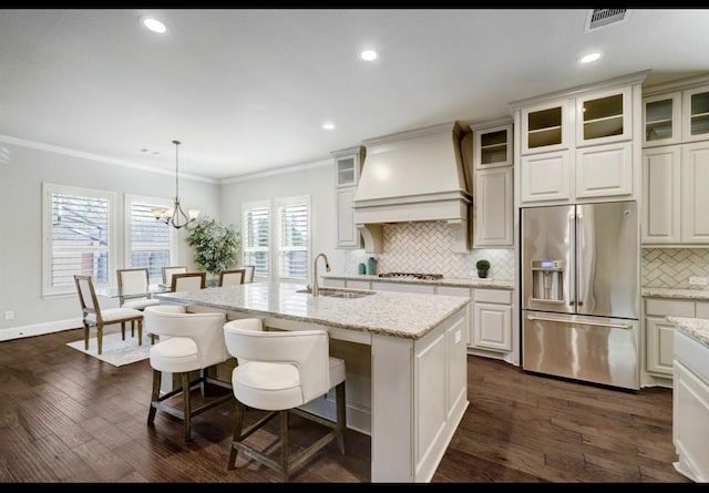 5011 Anthony Springs Ln, Sugar Land, TX 77479 - kitchen with high quality fridge, custom range hood, backsplash, ornamental molding, and dark wood-style flooring
