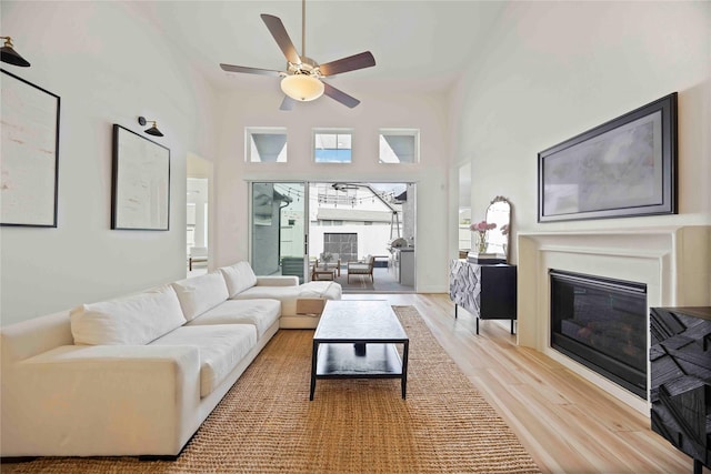 11822 Creekside Shore Cir, Cypress, TX 77433 - living area with light wood-style flooring, a ceiling fan, a glass covered fireplace, and a towering ceiling