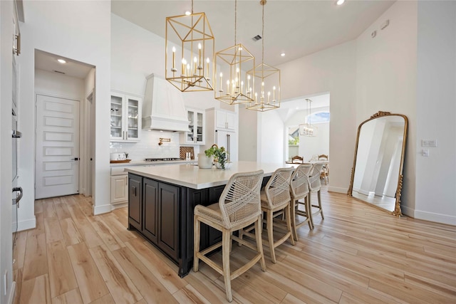 11822 Creekside Shore Cir, Cypress, TX 77433 - kitchen with custom exhaust hood, white cabinetry, a high ceiling, stovetop, and light countertops