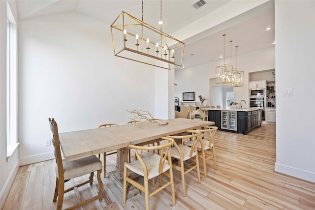 11822 Creekside Shore Cir, Cypress, TX 77433 - dining area featuring light wood finished floors, a chandelier, a high ceiling, recessed lighting, and wine cooler