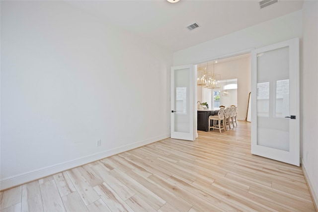 11822 Creekside Shore Cir, Cypress, TX 77433 - empty room featuring a chandelier, light wood-type flooring, and french doors