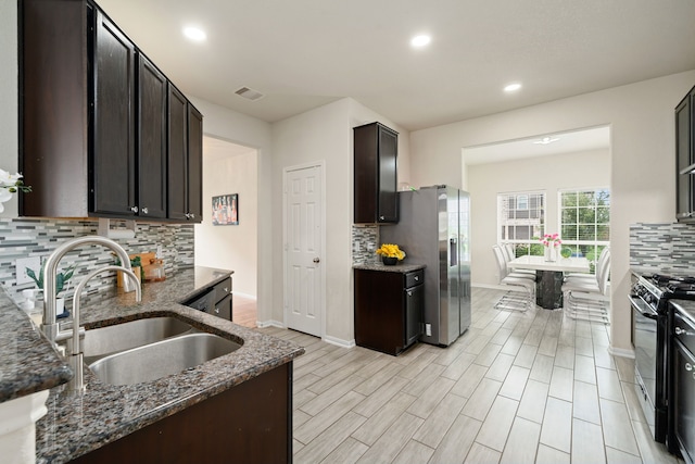 14722 Ruddy Duck Ln, Houston, TX 77049 - kitchen with gas range oven, backsplash, dark stone countertops, stainless steel fridge with ice dispenser, and recessed lighting