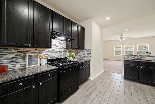 14722 Ruddy Duck Ln, Houston, TX 77049 - kitchen featuring black gas stove, under cabinet range hood, ceiling fan, and dark cabinets