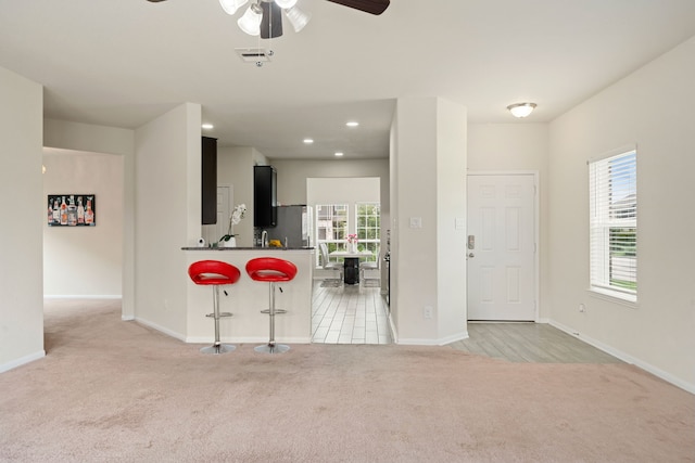 14722 Ruddy Duck Ln, Houston, TX 77049 - kitchen featuring light carpet, a ceiling fan, dark countertops, a breakfast bar area, and recessed lighting