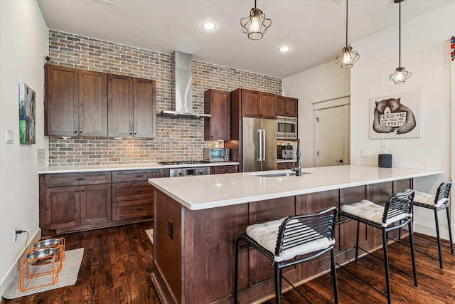 1422 Rosedale St, Houston, TX 77004 - kitchen featuring wall chimney range hood, appliances with stainless steel finishes, dark wood-type flooring, light countertops, and a kitchen breakfast bar