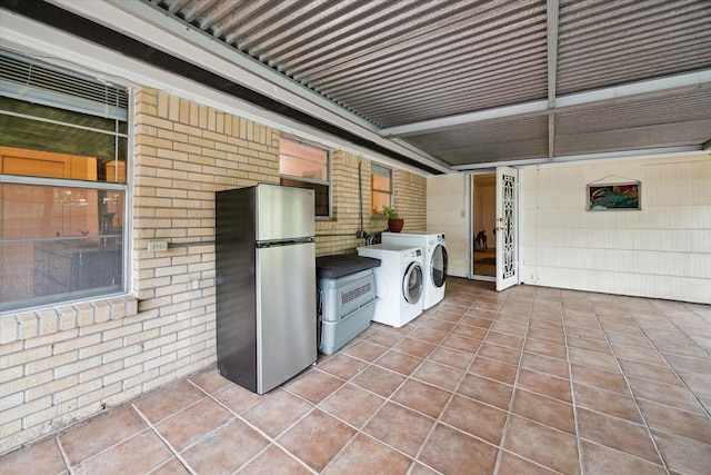 2110 Chippendale Rd, Houston, TX 77018 - laundry area featuring washer and clothes dryer, tile patterned floors, and brick wall