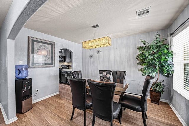 15307 Meandering Post Trl, Houston, TX 77044 - dining room featuring a chandelier, light wood finished floors, plenty of natural light, and a textured ceiling