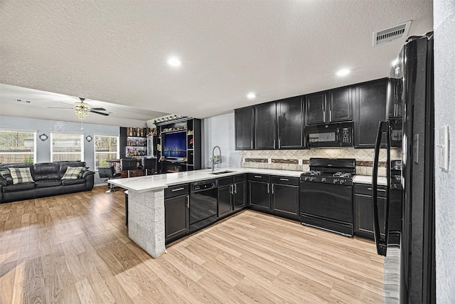 15307 Meandering Post Trl, Houston, TX 77044 - kitchen featuring black appliances, dark cabinets, a textured ceiling, light countertops, and a peninsula