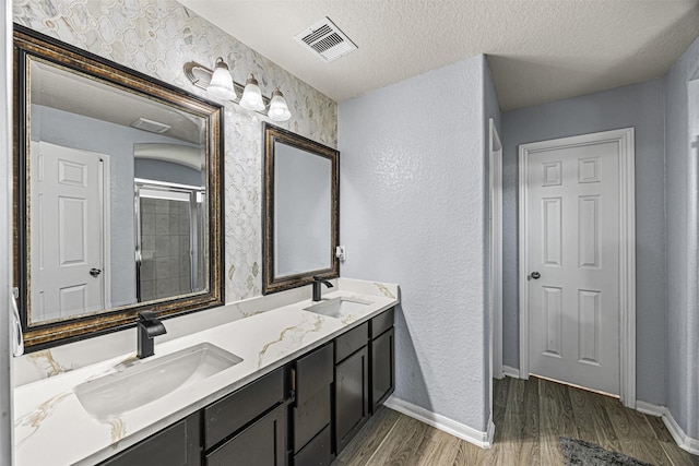 15307 Meandering Post Trl, Houston, TX 77044 - full bathroom featuring double vanity, wood finished floors, a shower with shower door, a textured ceiling, and a textured wall