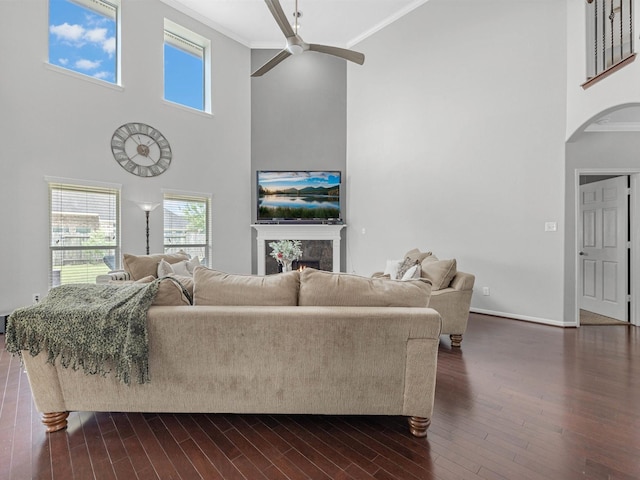 3310 Compass Ct, Conroe, TX 77301 - living room with ornamental molding, a towering ceiling, arched walkways, a ceiling fan, and a lit fireplace