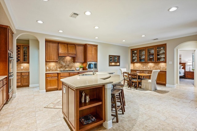 5222 Arcadia Glen Ln, Katy, TX 77494 - kitchen with arched walkways, decorative backsplash, recessed lighting, brown cabinets, and a kitchen breakfast bar