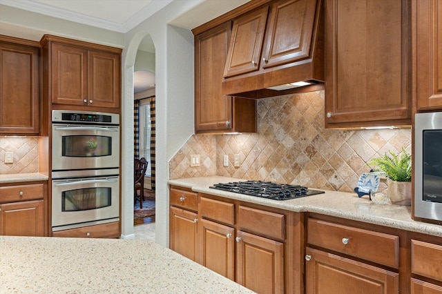 5222 Arcadia Glen Ln, Katy, TX 77494 - kitchen with stainless steel double oven, gas cooktop, custom range hood, arched walkways, and light stone counters