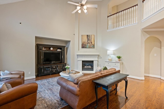 5222 Arcadia Glen Ln, Katy, TX 77494 - living area with arched walkways, a towering ceiling, a ceiling fan, wood finished floors, and a glass covered fireplace