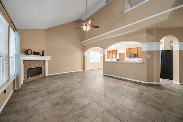 31322 Capella Cir, Tomball, TX 77375 - unfurnished living room featuring a ceiling fan, high vaulted ceiling, a fireplace, arched walkways, and tile patterned flooring