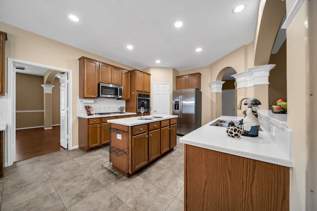 31322 Capella Cir, Tomball, TX 77375 - kitchen featuring appliances with stainless steel finishes, arched walkways, ornate columns, brown cabinets, and recessed lighting