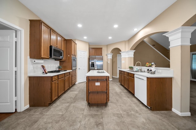 31322 Capella Cir, Tomball, TX 77375 - kitchen with appliances with stainless steel finishes, ornate columns, light countertops, brown cabinetry, and recessed lighting