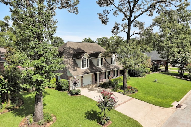 31322 Capella Cir, Tomball, TX 77375 - cape cod house with driveway, a front lawn, an attached garage, and brick siding