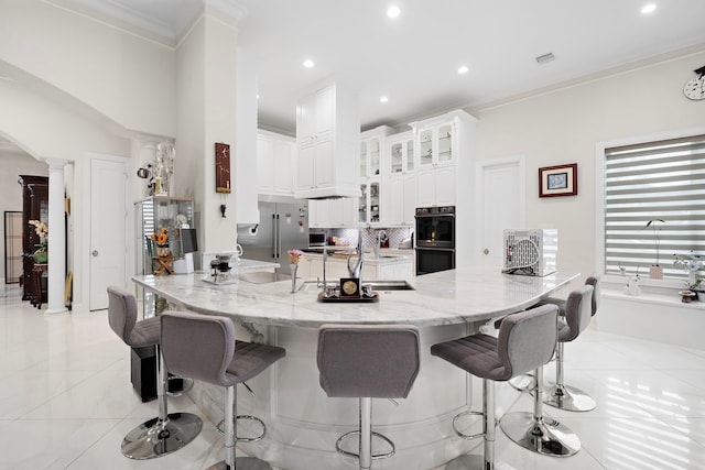 9761 Westview Dr, Houston, TX 77055 - kitchen with decorative columns, built in refrigerator, a breakfast bar area, crown molding, and white cabinetry