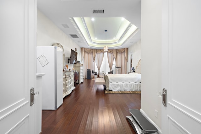 9761 Westview Dr, Houston, TX 77055 - bedroom with freestanding refrigerator, a raised ceiling, and dark wood-style flooring