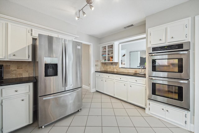 2902 Triway Ln, Houston, TX 77043 - kitchen with appliances with stainless steel finishes, dark countertops, white cabinetry, and tasteful backsplash