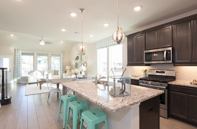 5631 Pearl Vista Dr, Katy, TX 77493 - kitchen with stainless steel appliances, dark brown cabinetry, light stone counters, backsplash, and recessed lighting