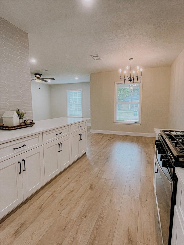 4521 Kingsbury St, Houston, TX 77021 - kitchen featuring gas stove, light wood-style flooring, a chandelier, white cabinets, and a textured ceiling