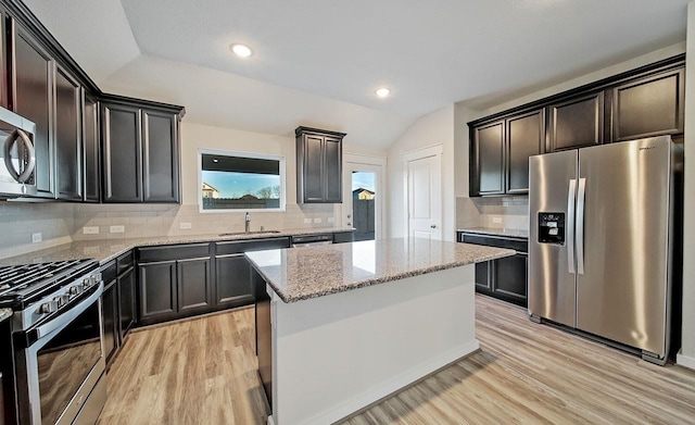 4446 Azalea Blossom Rd, Pinehurst, TX 77362 - kitchen with stainless steel appliances, light stone counters, light wood-style flooring, tasteful backsplash, and vaulted ceiling