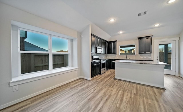4446 Azalea Blossom Rd, Pinehurst, TX 77362 - kitchen featuring stainless steel appliances, light wood-style floors, a kitchen island, recessed lighting, and light stone counters