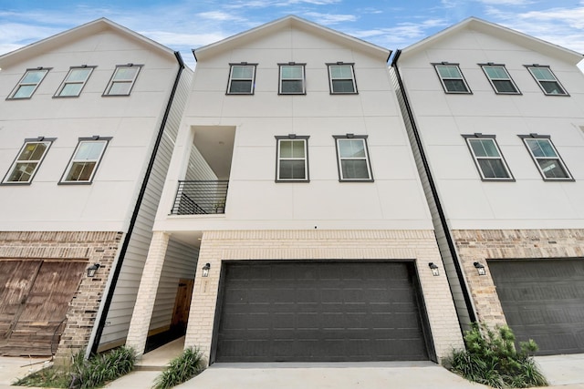 5502 Wheatley St Unit B, Houston, TX 77091 - view of property with a garage, brick siding, concrete driveway, and stucco siding