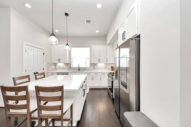 5502 Wheatley St Unit B, Houston, TX 77091 - kitchen featuring stainless steel appliances, light countertops, decorative backsplash, white cabinets, and a kitchen bar