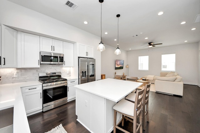 5502 Wheatley St Unit B, Houston, TX 77091 - kitchen featuring appliances with stainless steel finishes, backsplash, dark wood finished floors, a center island, and white cabinets
