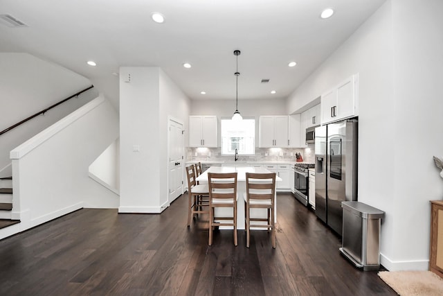 5502 Wheatley St Unit B, Houston, TX 77091 - kitchen featuring stainless steel appliances, dark wood finished floors, light countertops, white cabinets, and a breakfast bar area