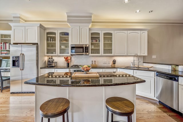 1013 Crocker St, Houston, TX 77019 - kitchen with appliances with stainless steel finishes, a breakfast bar, ornamental molding, light wood-style floors, and recessed lighting