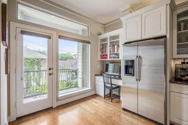 1013 Crocker St, Houston, TX 77019 - kitchen with stainless steel fridge with ice dispenser, dark countertops, crown molding, plenty of natural light, and light wood-type flooring