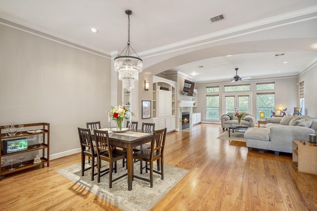 1013 Crocker St, Houston, TX 77019 - dining space with a ceiling fan, arched walkways, light wood-style floors, crown molding, and a fireplace with flush hearth