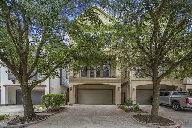 1013 Crocker St, Houston, TX 77019 - view of front of property featuring a balcony, decorative driveway, stucco siding, and a garage
