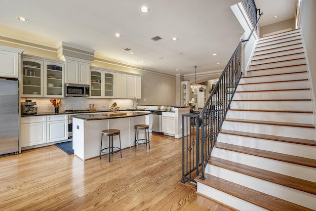 1013 Crocker St, Houston, TX 77019 - kitchen with stainless steel appliances, a kitchen island, a breakfast bar, dark countertops, and light wood finished floors