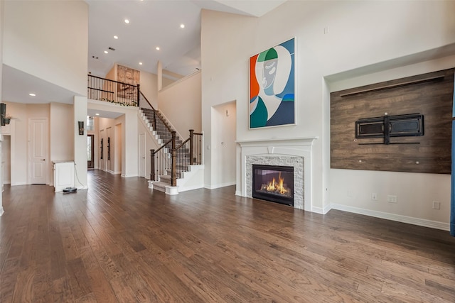 14062 Dunsmore Landing Dr, Houston, TX 77059 - unfurnished living room featuring wood finished floors, a towering ceiling, a glass covered fireplace, stairs, and recessed lighting
