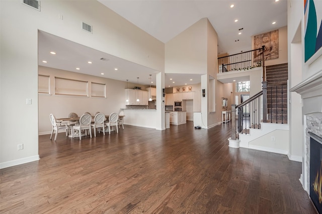 14062 Dunsmore Landing Dr, Houston, TX 77059 - living room featuring a towering ceiling, a lit fireplace, wood finished floors, stairway, and recessed lighting