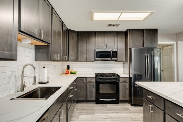 107 Sage St, Lake Jackson, TX 77566 - kitchen with appliances with stainless steel finishes, dark brown cabinetry, and light wood-type flooring