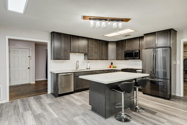107 Sage St, Lake Jackson, TX 77566 - kitchen featuring stainless steel appliances, dark brown cabinetry, light wood-style flooring, and tasteful backsplash