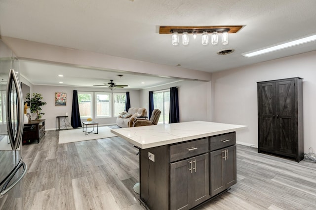 107 Sage St, Lake Jackson, TX 77566 - kitchen with light wood-type flooring, light stone countertops, freestanding refrigerator, open floor plan, and a kitchen island