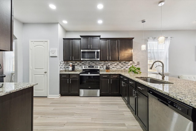 21022 Solstice Point Dr, Hockley, TX 77447 - kitchen with stainless steel appliances, light wood-type flooring, light stone counters, backsplash, and decorative light fixtures