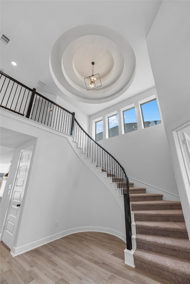 3173 Stingray Cove Dr, Katy, TX 77493 - stairs with a tray ceiling, wood finished floors, a high ceiling, and a chandelier